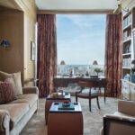 Elegant study with city views, patterned drapes, and a vintage writing desk.