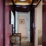 Hallway with high-gloss burgundy walls, a gold barrel ceiling, and animal-print accent chair.