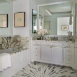 Light and airy bathroom with marble flooring, white cabinets, and a soaking tub with marble surround.