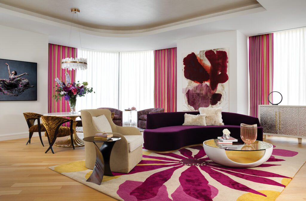 Living room with curved purple sofa, floral rug, and bold modern artwork.