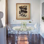 Contemporary dining area with Lucite chairs, round table, and bold black-and-white artwork in a luxury Boston home.