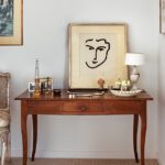 Wooden console table displaying a Matisse portrait sketch and decorative objects in a refined Boston apartment.