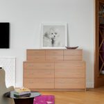 Modern wood dresser with framed black-and-white artwork and colorful rug accents.