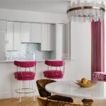 Sleek kitchen with glossy white cabinets, mosaic backsplash, and magenta bar stools.
