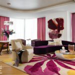 Living room with curved purple sofa, floral rug, and bold modern artwork.