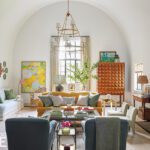 Living room with vaulted ceiling, eclectic furnishings, and layered artwork