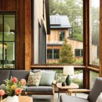 Screened porch seating area with wood furniture, gray cushions, and garden views.