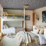 Kids’ bunk room with patterned ceiling, layered beds, and warm neutral bedding.