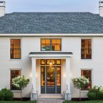 White-painted brick home with symmetrical windows and landscaped entryway.