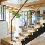 Contemporary staircase with floating wood steps, glass railing, and open foyer design.