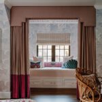 Built-in daybed framed by tailored drapery with decorative pillows in a soft pink and blue bedroom alcove