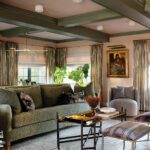 Comfortable family room with green textured sofa, eclectic seating, gold ceiling beams, and curated artwork