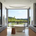 Freestanding bathtub framed by a large picture window with sweeping mountain views.