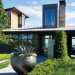 Contemporary home facade with large agave planter and vertical chimney structure.