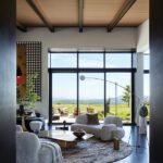 Modern living room with sculptural furniture and glass walls opening to mountain vistas.