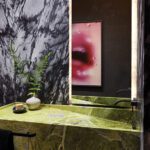 Bold powder room with dramatic marble wall, green stone vanity, and modern lighting.