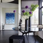 Contemporary vignette with round black table, sculptural vases, and large windows.