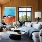 Cozy seating area in wood-paneled bedroom with modern furniture and bold artwork.