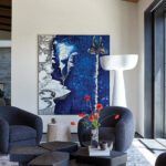 Modern lounge area with abstract blue artwork and curved chairs around a wood coffee table.