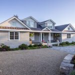 Shingle-style coastal home with landscaped front garden and water views