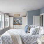 Light-filled primary bedroom with waterfront views and blue walls