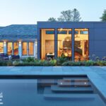 Modern home with floor-to-ceiling windows overlooking a pool and landscaped garden