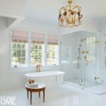 Luxury white bathroom with freestanding tub, glass shower, and gold accents