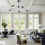 Modern living room with black sectional sofa, white accent chairs, and checkered rug