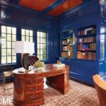 Classic office with glossy blue walls, wood desk, and built-in bookshelves