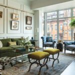 Living room with green velvet sofa, blue patterned chairs, and gallery wall.