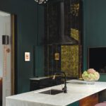 Dramatic kitchen with marble waterfall island and dark green walls.