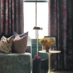 Seating nook with textured pillows, side tables, and patterned drapery.