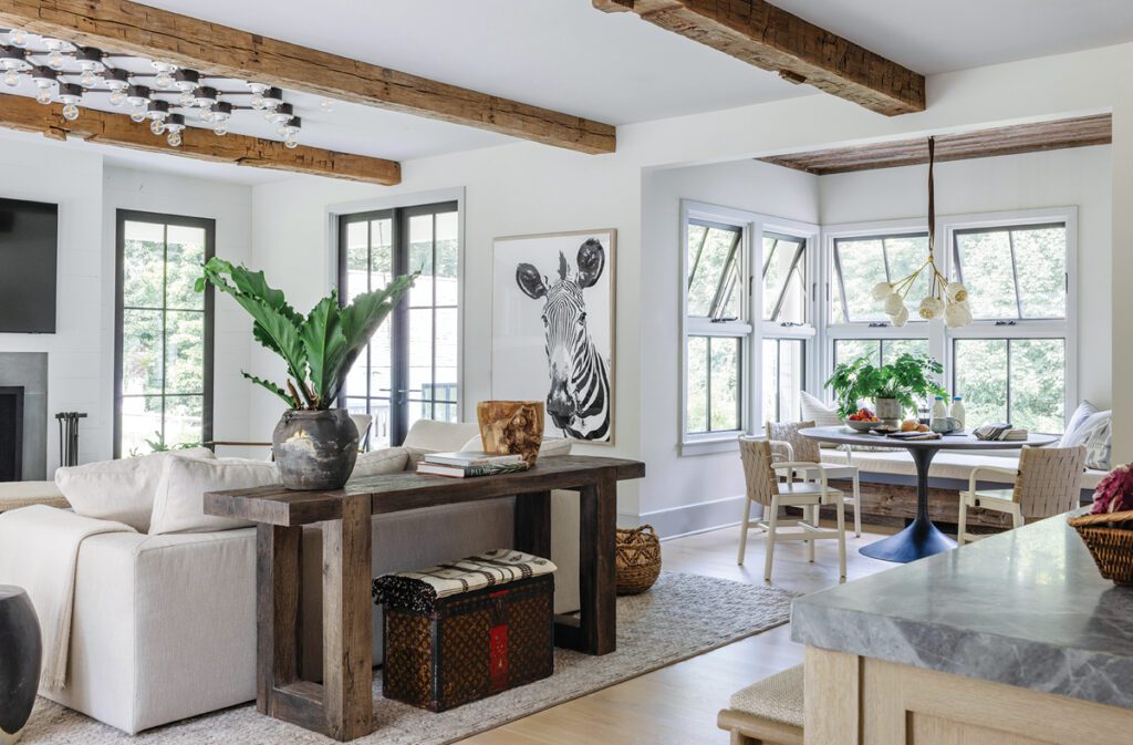 Open concept living and dining area with exposed wood beams, zebra artwork, and cozy breakfast nook.