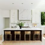 Modern kitchen with large marble island, pendant lighting, and wood cabinetry.