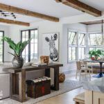 Open concept living and dining area with exposed wood beams, zebra artwork, and cozy breakfast nook.