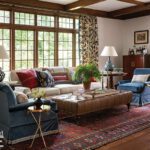 Traditional living room with beamed ceiling, patterned drapery, and leather ottoman.
