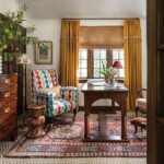 Home office with patterned wingback chair, mustard drapery, and antique desk.