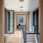 Bright hallway with wood trim, black-framed doors, and vintage rug.