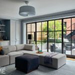 Lower-level lounge with sectional sofa, built-in shelving, and glass doors to outdoor terrace.