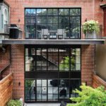 Boston townhouse rear exterior with red brick façade, black-framed windows, balconies, and garden terrace.
