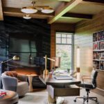 Modern home office with wood paneling, marble fireplace, and sculptural brass desk
