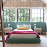 Colorful girl’s bedroom featuring mint-green bed, pink blanket, and bubble chandelier under vaulted ceiling with patterned wallpaper.