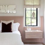 Blush pink bedroom with upholstered bed, textured wall art, and pendant light beside a modern nightstand.