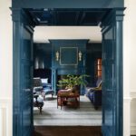 Dramatic entryway framing a navy paneled living room with fireplace
