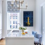 Bright kitchen with marble island, blue barstools, and modern art.