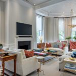 Elegant living room with layered seating and neutral palette accented in red and blue.