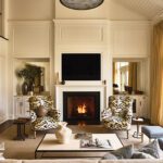 Light-filled living room with patterned armchairs and classic white fireplace