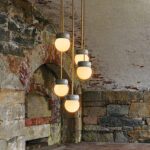 Modern pendant lights with glowing glass orbs in a historic stone interior