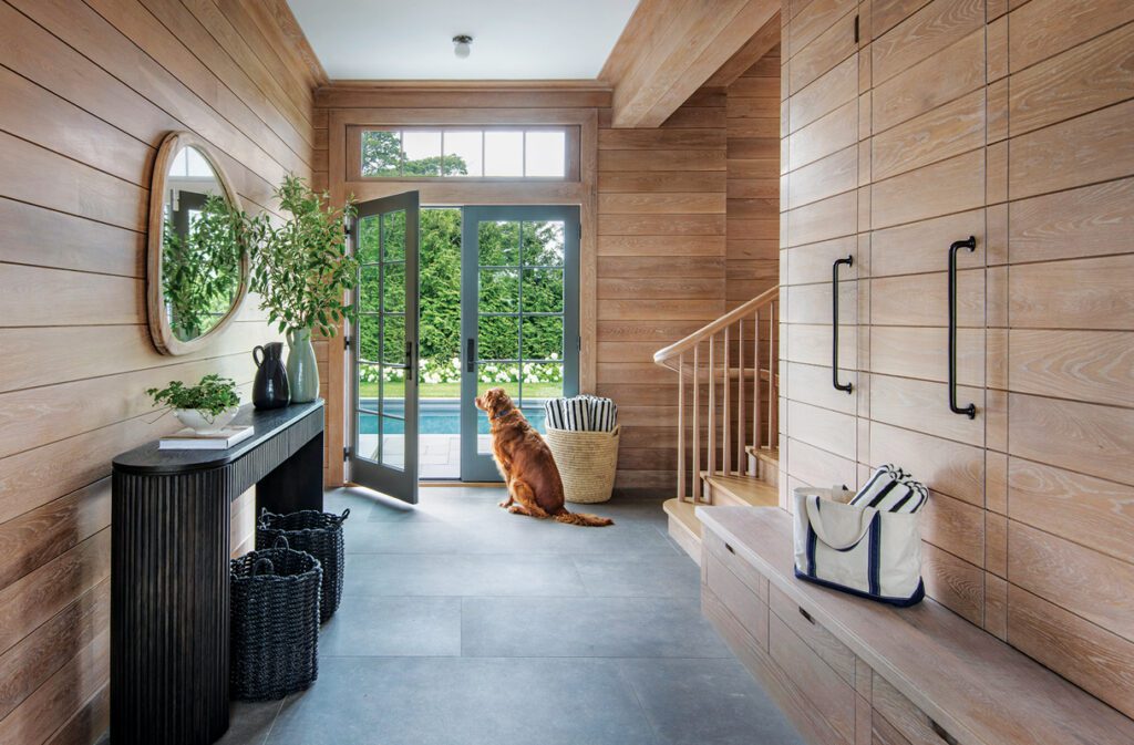 Mudroom entry with wood paneling, built-in storage, and glass doors opening to backyard.
