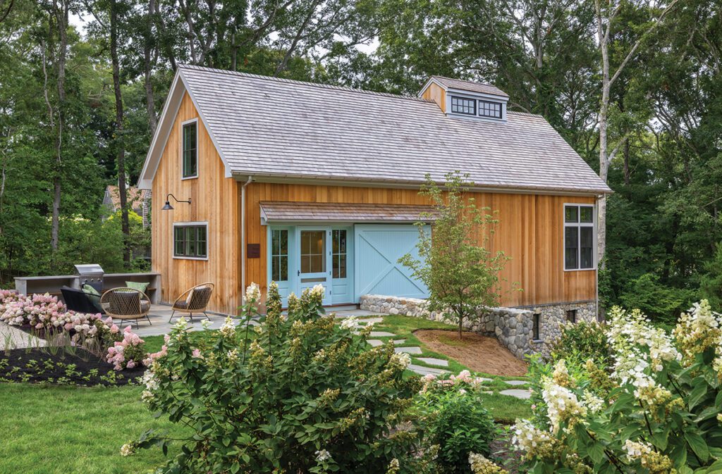Rear exterior of cedar cottage with stone foundation and wooded landscape.